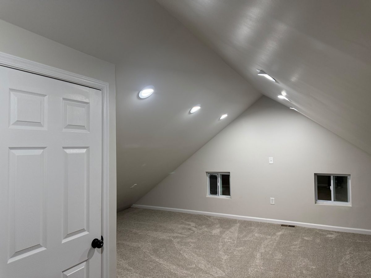 Finished attic room with sloped drywall ceilings, recessed lights and new carpet