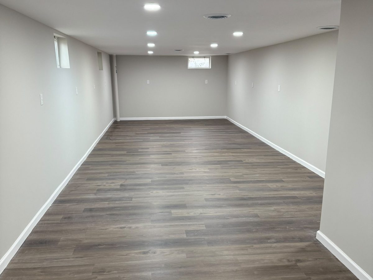 Finished basement with new drywall, recessed lighting and gray vinyl plank flooring