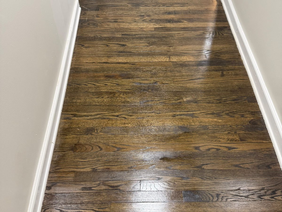Refinished oak hardwood hallway floor with a dark stain and white baseboard