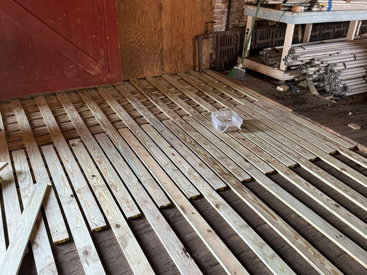 Old floor in a brick-walled space with new pressure-treated sleepers laid and leveled