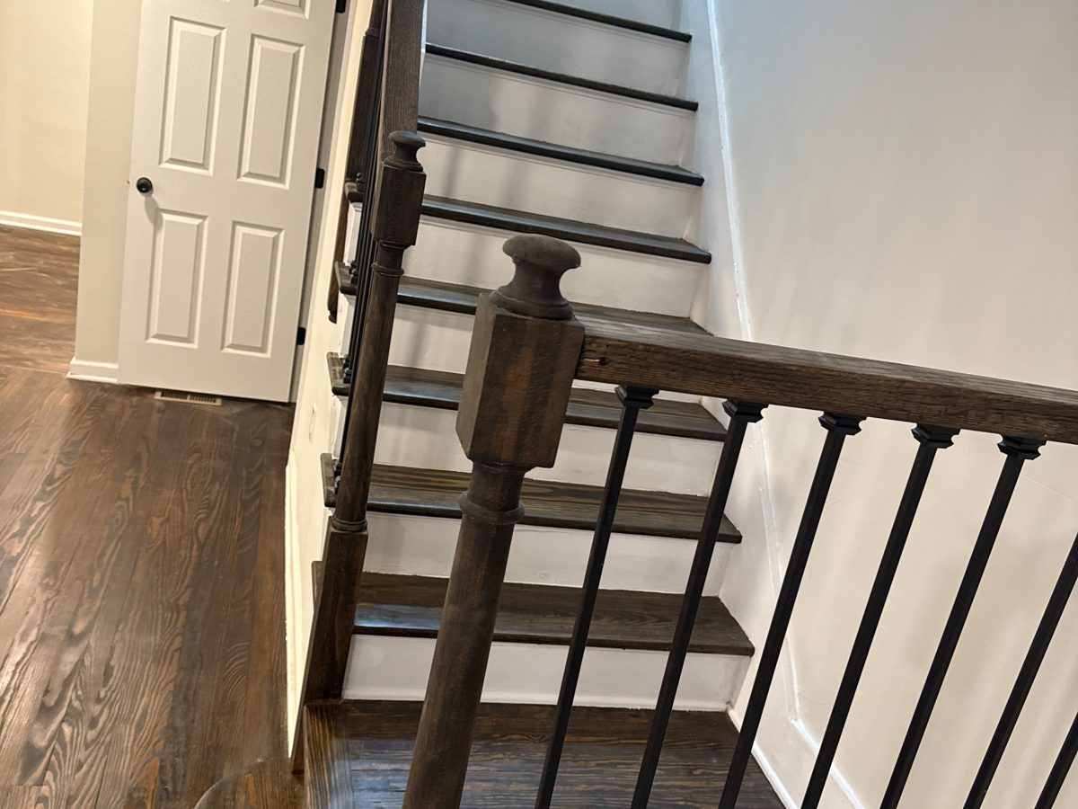 Oak staircase with dark-stained treads, white risers and black iron balusters